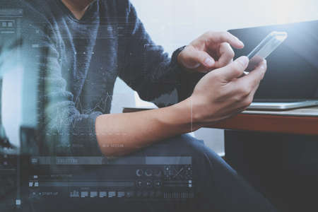 Designer hand using mobile payments online shopping,omni channel,laptop computer on wooden desk,digital screen graphic virtual icons,graph,diagramの写真素材