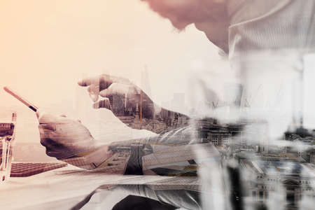 Double exposure of businessman hand using mobile payments online shopping,omni channel,laptop computer on wooden desk,London architecture bulidingsの写真素材