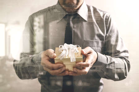 gift giving,businessman hand holding a gift box in a gesture of giving front view,filter effect,icons graphicの写真素材
