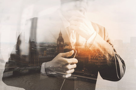 Double exposure of success businessman holding digital tablet computer with London...