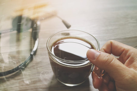 Hand holding Coffee cup or tea and voip headset,memo book on wooden table,filter effect,icon screen
