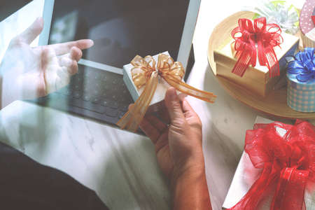 Gift giving Creative Hand choosing and hand with gift. Gift delivery, surprise,tablet computer docking smart keyboard smart phone on mable desk,vintage film effectの写真素材