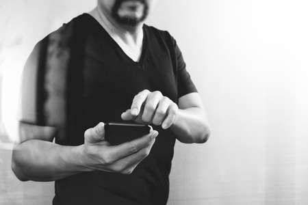 Designer hand using smart phone for mobile payments online shopping,omni channel,on white background,black white,front viewの写真素材