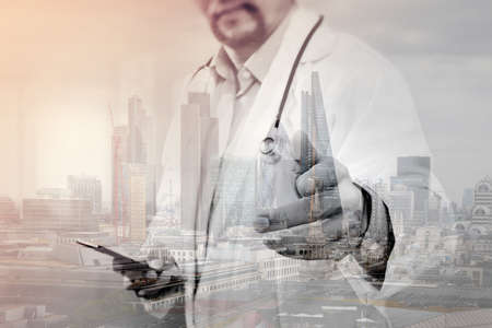 Double exposure of Medical technology concept. Doctor hand working with modern smart phone with medical chart interface,multi channel connection,London buildingsの写真素材