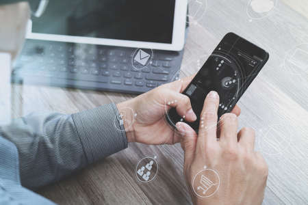 Hand using mobile payments online shopping,omni channel,icon customer network,in modern office wooden desk, graphic interface screen,eyeglass,filterの写真素材