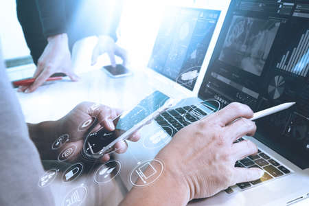 Co worker Designer hand using mobile payments online shopping,omni channel,in modern office wooden desk,icons graphic interface screen,eyeglass,filterの写真素材