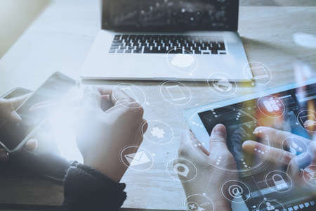 Designer hand using mobile payments online shopping,omni channel,in modern office wooden desk,icons graphic interface screen,eyeglass,filterの写真素材