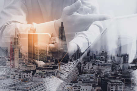 Double exposure of success businessman using smart phone,digital tablet docking smart keyboard  with London building,city,omnichannelの写真素材