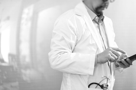 Medical technology concept. Doctor hand working with modern smart phone with medical chart interface,multi channel connection,white background,black whiteの写真素材