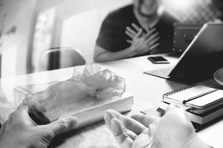 business creative designer hand giving his colleague Christmas present in office,black and whiteの写真素材