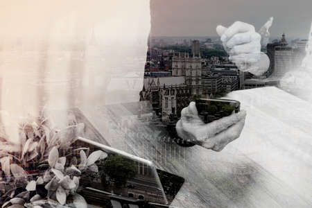 Double exposure of Businessman hand using mobile payments online shopping,omni channel,in modern office wooden desk,London city buildingsの写真素材
