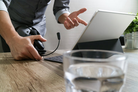 business man using VOIP headset with digital tablet computer docking smart keyboard, concept communication, it support,on wood deskの写真素材