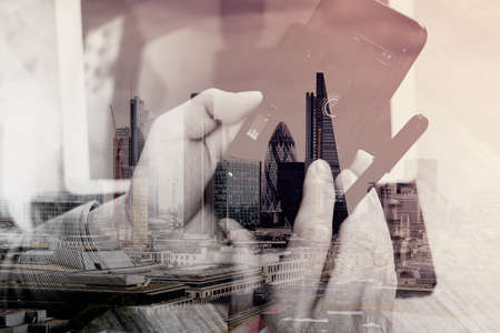 Double exposure of Hand using mobile payments online shopping,omni channel,icon customer network,in modern office wooden desk,London city buildings,eyeglassの写真素材