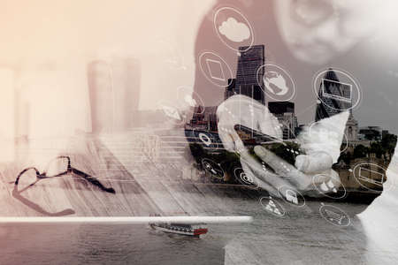 Double exposure of Businessman hand using mobile payments online shopping,omni channel,in modern office wooden desk,London city buildings,eyeglassの写真素材