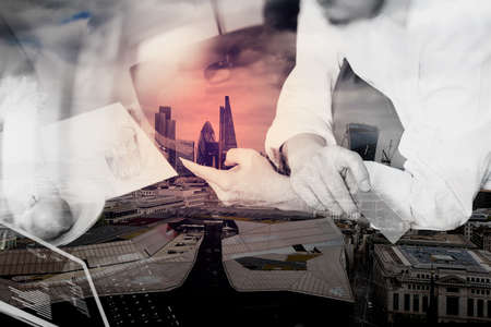 double exposure of hipster hand using smart phone and laptop compter,holding credit card payments online business,sitting on sofa in living room,green apples in wooden tray,London cityの写真素材