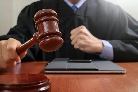 justice and law concept.Male judge in a courtroom striking the gavel,working with digital tablet...