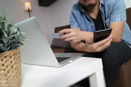hipster hand using smart phone and laptop compter,holding cradit card payments online...