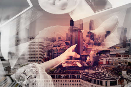 double exposure of hipster hand using smart phone for mobile payments online business,glass of water,sitting on sofa in living room,green apples in wooden tray,London buildings cityの写真素材