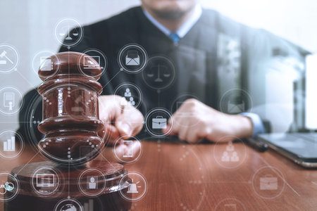 justice and law concept.Male judge in a courtroom striking the gavel,working with digital tablet...