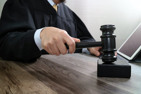 justice and law concept.Male judge in a courtroom striking the gavel,working with digital tablet...