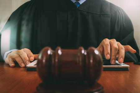 justice and law concept.Male judge in a courtroom striking the gavel,working with digital tablet...