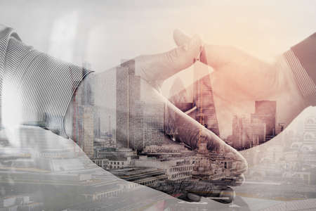 Double exposure of Business partnership meeting concept.photo businessmans handshake. Successful businessmen handshaking after perfect deal.close up,London architecture cityの写真素材