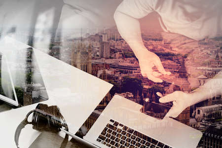 double exposure of hipster hand using smart phone and laptop compter,digital tablet docking keyboard,holding cradit card payments online business,sitting on sofa in living room,work at home concept,London architecture cityの写真素材
