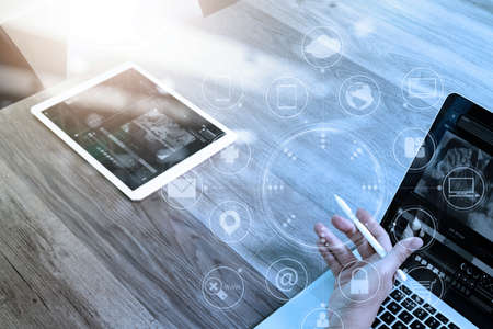 Designer Businessman hand using smart phone,mobile payments online shopping,omni channel,digital tablet docking keyboard computer in modern office on wooden desk,virtual interface icons screenの写真素材