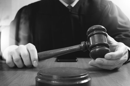 justice and law concept.Male judge in a courtroom striking the gavel,working with digital tablet...