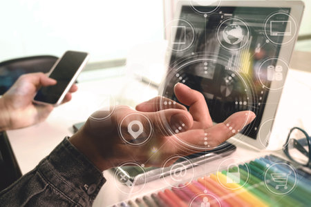 Designer Businessman hand using smart phone,mobile payments online shopping,omni channel,digital tablet docking keyboard computer in modern office on wooden desk,virtual interface icons screenの写真素材