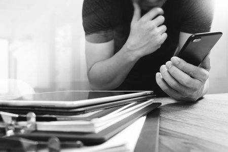 Designer hand using mobile payments online shopping,omni channel,in modern office wooden desk,icons...