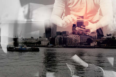 double exposure of hipster hand using digital tablet docking keyboard and smart phone for mobile payments online business,omni channel,sitting on sofa in living room,London architecture cityの写真素材