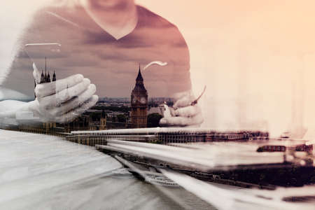 Double exposure of Designer hand using mobile payments online shopping,omni channel,in modern office wooden desk,London city buildings,eyeglassの写真素材