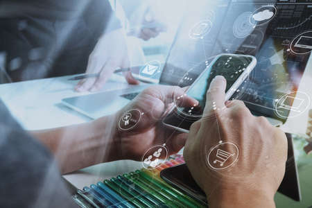 Designer Businessman hand using smart phone,mobile payments online shopping,omni channel,digital tablet docking keyboard computer in modern office on wooden desk,virtual interface icons screenの写真素材