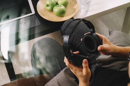 hipster hand holding headphone,using digital tablet docking keyboard and mobile payments online business,omni channel,sitting on sofa in living room,green apples in wooden tray,filter effectの写真素材