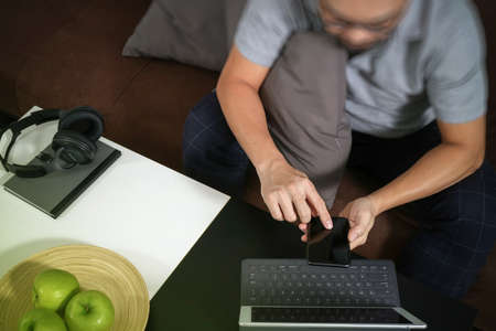 hipster hand using digital tablet docking keyboard and smart phone for mobile payments online business,omni channel,sitting on sofa in living room,green apples in wooden trayの写真素材