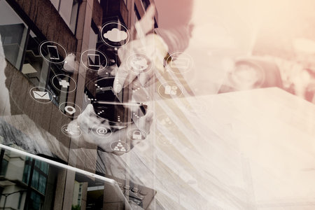 Double exposure of Businessman hand using mobile payments online shopping,omni channel,in modern office wooden desk,London city buildings,eyeglassの写真素材