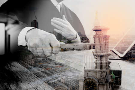 double exposure of justice and law concept.Male judge in a courtroom striking the gavel,working with digital tablet computer docking keyboard on wood table,London architecture cityの写真素材