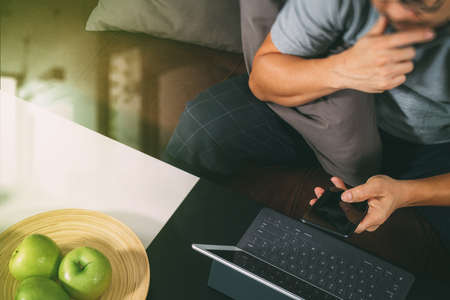 hipster hand using digital tablet docking keyboard and smart phone for mobile payments online business,omni channel,sitting on sofa in living room,green apples in wooden tray,filter effectの写真素材