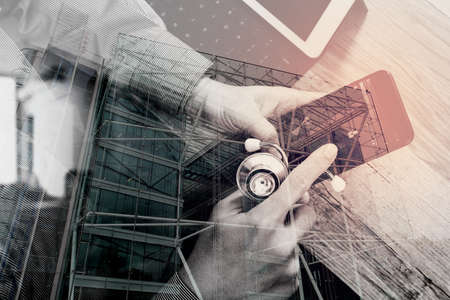 double exposure of medical doctor hand working with smart phone,digital tablet computer,stethoscope eyeglass,on wooden desk,London architecture cityの写真素材