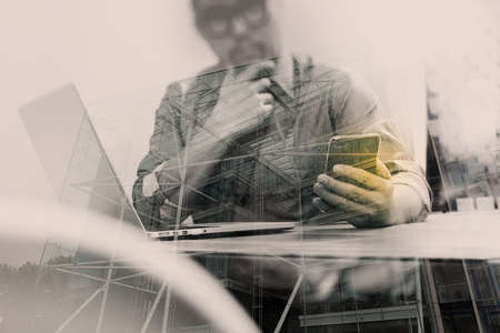 Double exposure of businessman hand using mobile payments online shopping,omni channel,laptop computer on wooden desk,London architecture bulidingsの写真素材