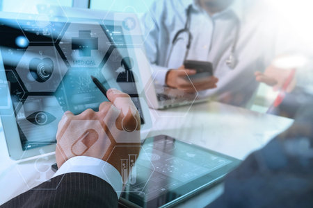 medical doctor hand working with smart phone,digital tablet computer,stethoscope eyeglass,on wooden...