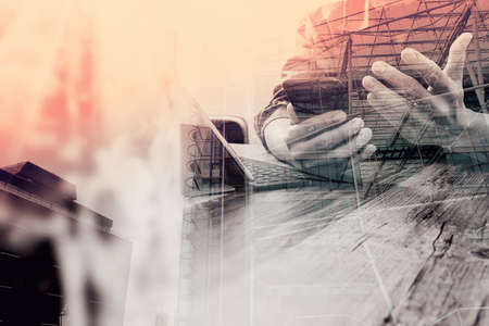 double exposure of businessman hand using smart phone,mobile payments online shopping,omni channel,digital tablet docking keyboard computer,flower glass vase on wooden desk,London architecture cityの写真素材