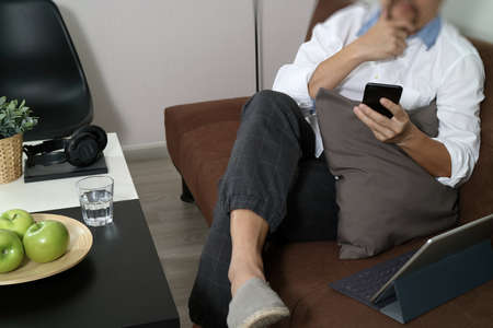 hipster hand using smart phone for mobile payments online business,headphone,sitting on sofa in living room,green apples in wooden trayの写真素材