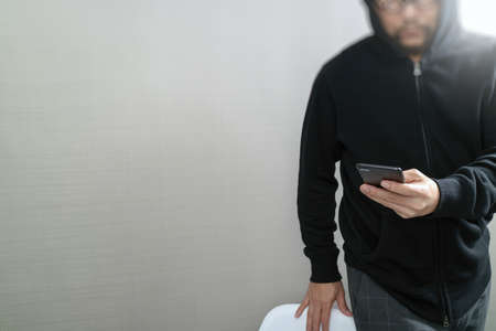 hipster male in a hood hand using mobile phone payments online shopping,omni channel,front viewの写真素材