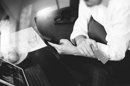 hipster hand using smart phone and laptop compter,holding credit card payments online business,sitting on sofa in living room,green apples in wooden tray,black and whiteの写真素材