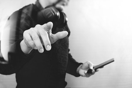 Businessman hand pressing an imaginary button,holding smart phone,blank digital screen graphic virtual icons,graph,diagram,black whiteの写真素材