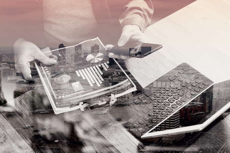 double exposure of businessman hand using smart phone,mobile payments online shopping,omni channel,digital tablet docking keyboard computer,documnets,in modern office on wooden desk,London architecture cityの写真素材
