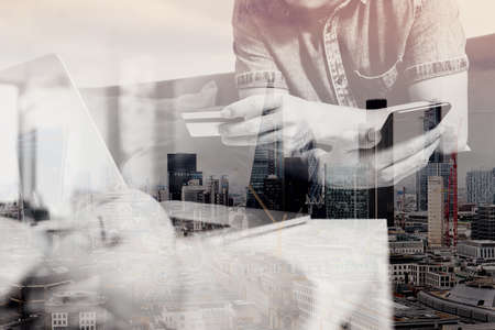 double exposure of hipster hand using smart phone and laptop compter,holding cradit card payments online business,sitting on sofa in living room,green apples in wooden tray,London city buildingsの写真素材