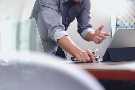smart medical doctor hand working with smart phone,digital tablet computer,stethoscope eyeglass,on wood desk,filter effectの写真素材